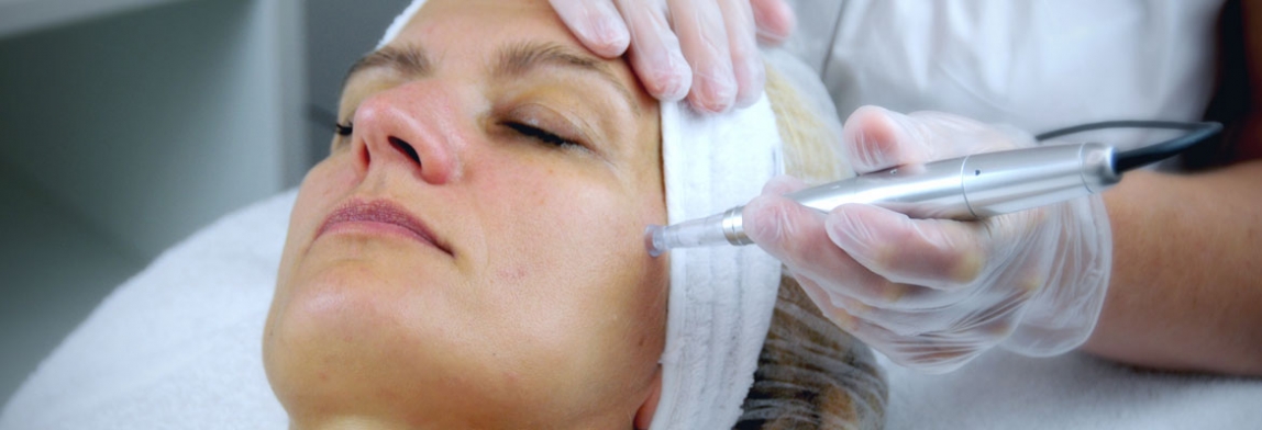 Frau liegt entspannt auf einer Behandlungsliege und erhält eine apparative Gesichtsbehandlung mit kosmetischem Gerät