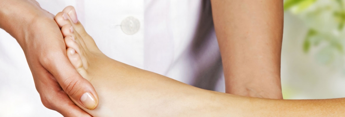 Fußmassage im Wellness- oder Kosmetikbereich: Eine behandelte Person massiert den Fuß einer liegenden Kundin mit beiden Händen